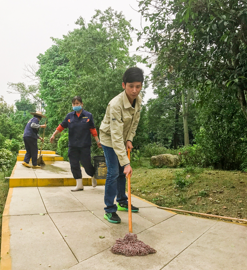 卢健将同志（右一）协助保洁人员清洗园道 