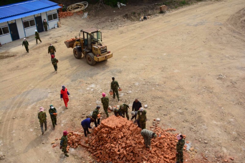 大铲车吊起alc墙板堆放到空闲场地,小铲车搬运红砖,部分义工装车卸