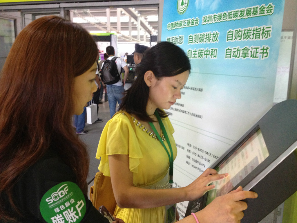 在基金会绿色展会专区内，参观者在工作人员指导下自测碳排放